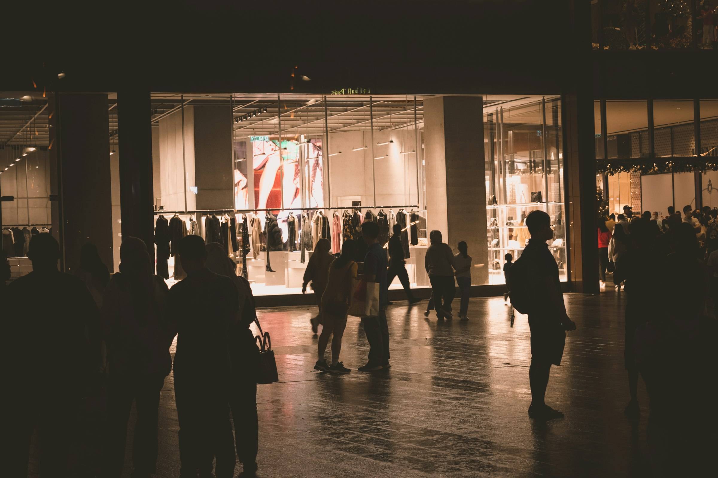 Shoppers silhouetted against a lit shop window