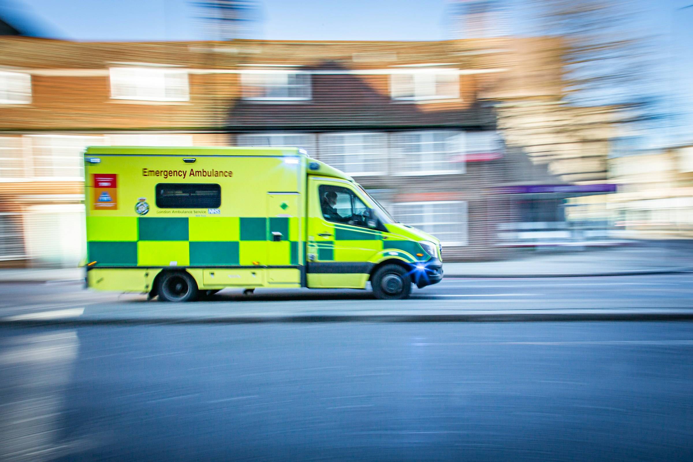 An NHS ambulance at speed on a British street
