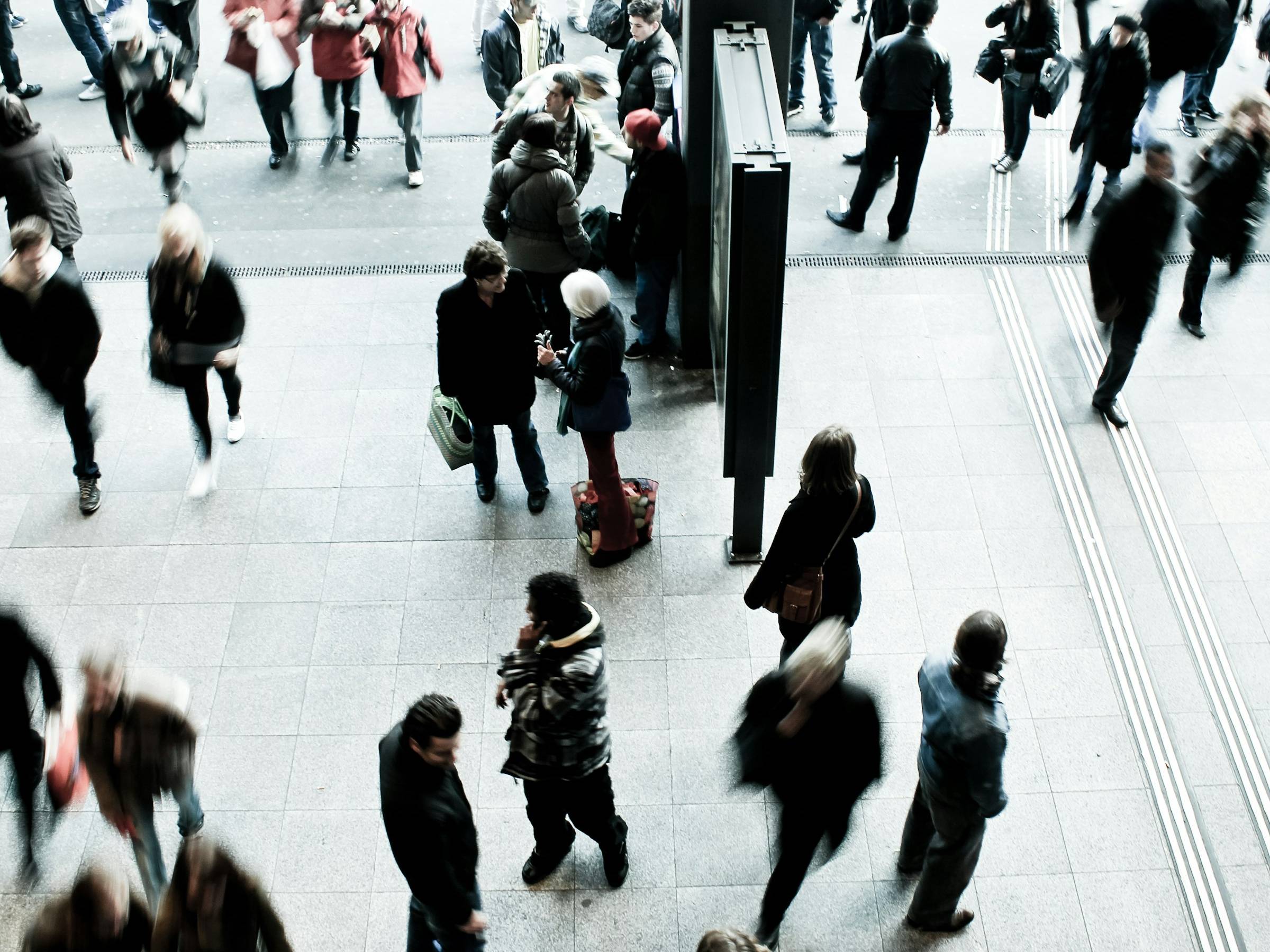 Commuters crossing a station concourse, seen from above